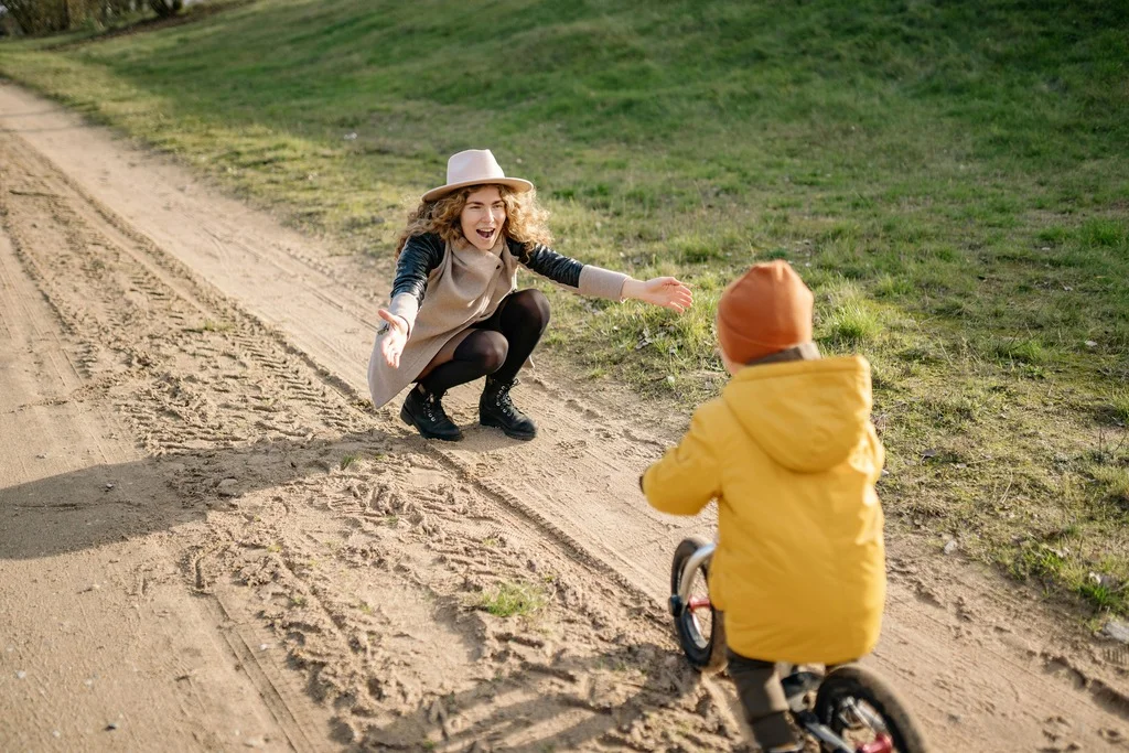 Maminka podporující své dítě v jízdě na kole